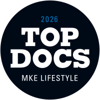 A black circular badge with white text reads TOP DOCS MKE LIFESTYLE and smaller blue text at the top reads 2026.