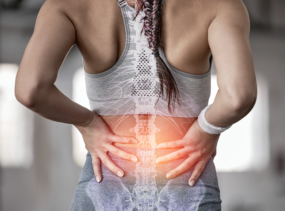 A woman in workout clothing holds her lower back in pain. An illustration of her spine is superimposed, highlighting the discomfort. The image raises awareness that conditions like hearing loss often coexist with chronic pain issues.