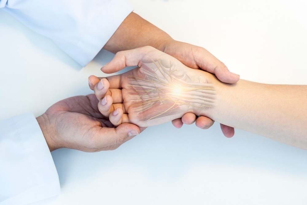 A doctor holds a patients hand, with an anatomical illustration overlay showing nerves in the hand and wrist, highlighting the area with a glowing effect.